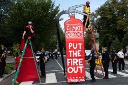 A group of Extinction Rebellion protesters hold the intersection of Massachusetts Avenue and 18th streets near Dupont Circle, chaining themselves to ladders. (WTOP/Alejandro Alvarez)