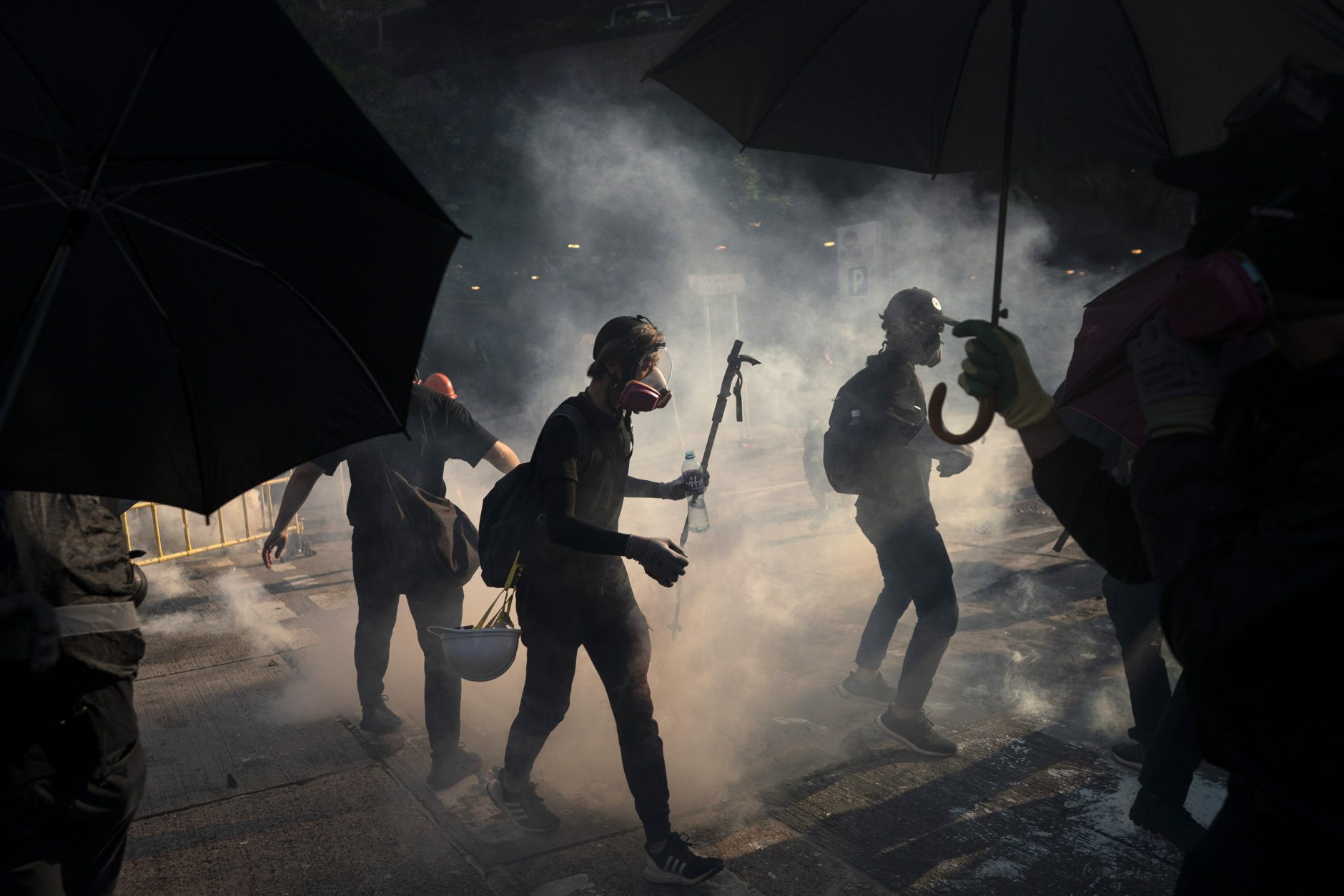 anti-government protesters surrounded by smoke in hong kong