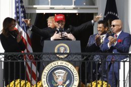 President Donald Trump hugs Washington Nationals catcher Kurt Suzuki, during an event to honor the 2019 World Series champion Washington Nationals on the balcony of the White House, Monday, Nov. 4, 2019, in Washington, as First Lady Melania Trump, left, and Washington Nationals coach Dave Martinez, second from right and general manager Mike Rizzo, far right, look on. Suzuki is wearing a Make America Great Again hat. (AP Photo/Patrick Semansky)