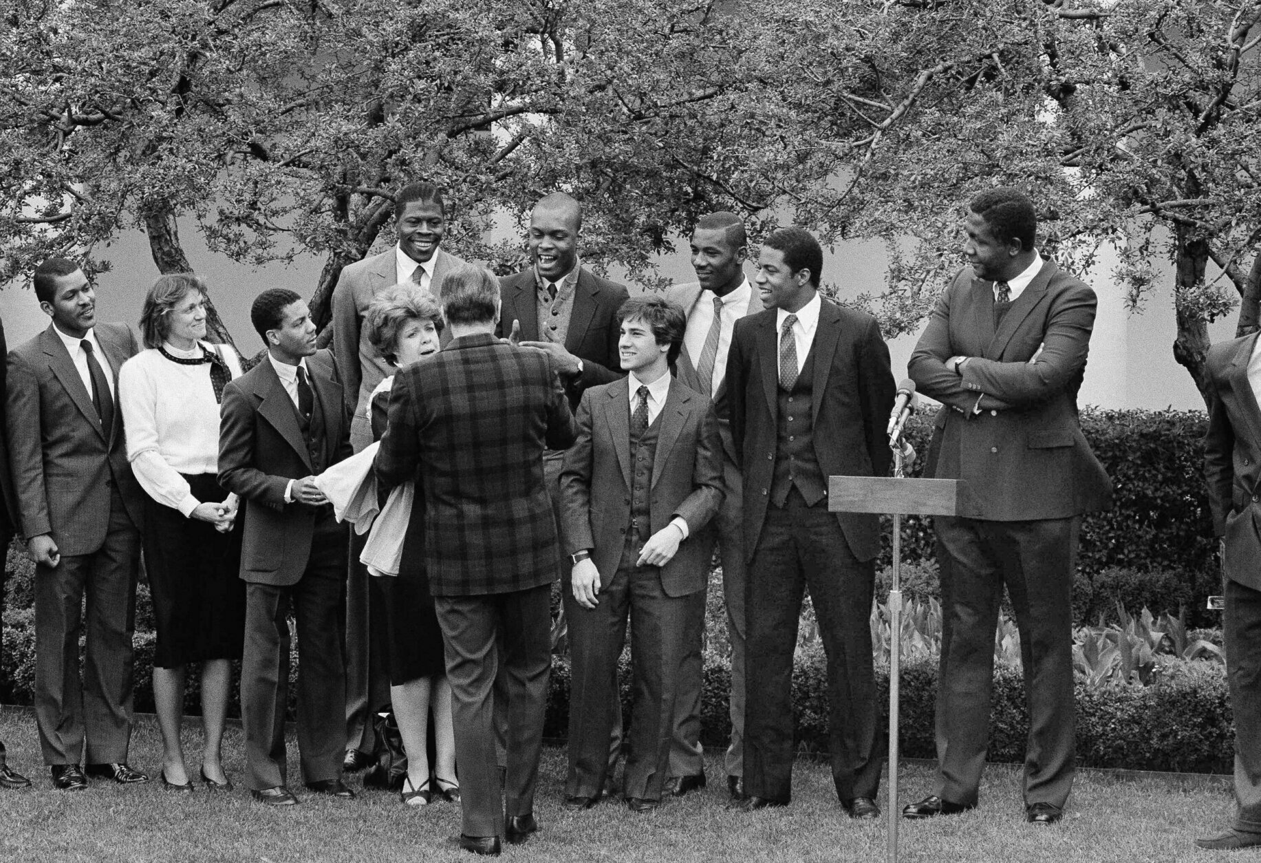 U.S.President Ronald Reagan shakes hands with Patrick Ewing, left, and Michael Graham, right, as Georgetown University academic coordinator Mary Fenlon looks on, during a ceremony for the Georgetown University NCAA Champion basketball team, in the Rose Garden of the White House, Saturday, April 7, 1984 in Washington. (AP Photo/Charles Tasnadi)