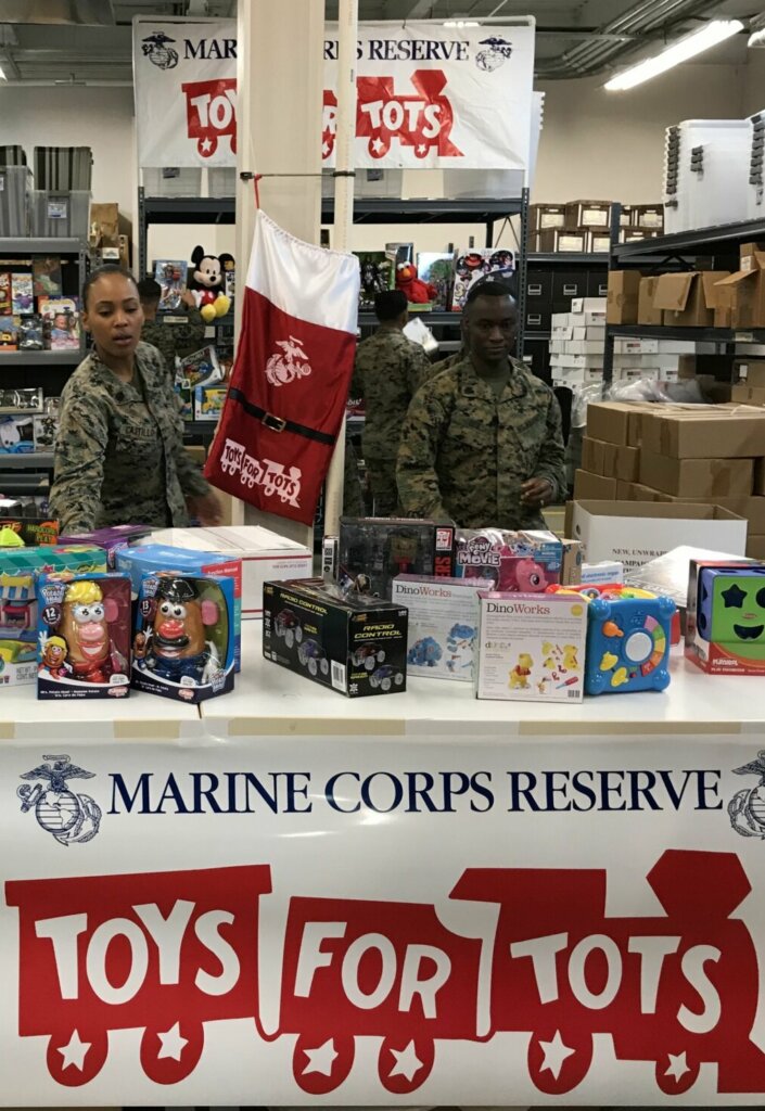 Marines behind a table of toys for children.