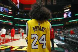 A fan watches warmups while wearing a Kobe Bryant jersey after news reports of his death in a helicopter crash prior to an NBA basketball game between the Washington Wizards and the Atlanta Hawks, Sunday, Jan. 26, 2020, in Atlanta. (AP Photo/Todd Kirkland)