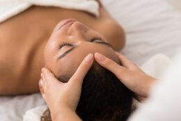 African-american woman enjoying anti aging facial massage in spa salon