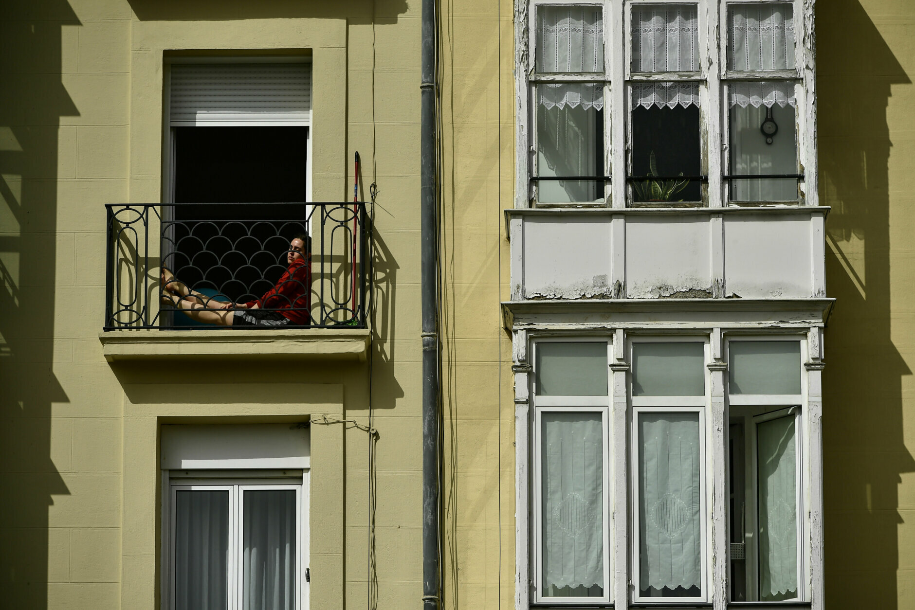 A woman rests on the balcony of a building as people stay in their houses to prevent the spread of coronavirus,, in Vitoria, northern Spain, Thursday, March 19, 2020. Spain will mobilize 200 billion euros or the equivalent to one fifth of the country's annual output in loans, credit guarantees and subsidies for workers and vulnerable citizens, Prime Minister Pedro Sanchez announced Tuesday. For most people, the new coronavirus causes only mild or moderate symptoms. For some, it can cause more severe illness, especially in older adults and people with existing health problems.