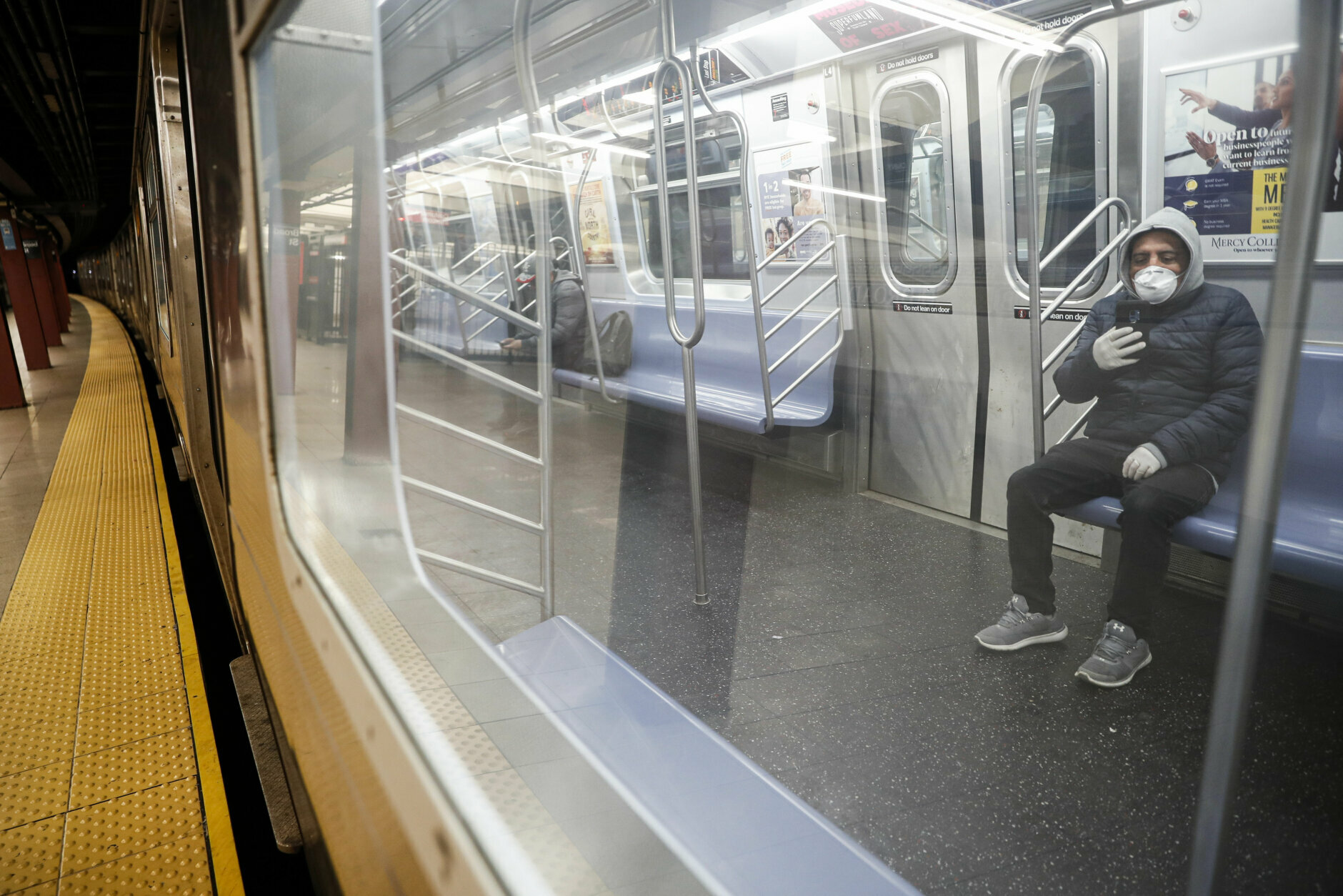 Subway riders wear protective masks and gloves on a sparsely populated car during morning hours due to COVID-19 concerns that are driving down ridership, Thursday, March 19, 2020, in New York. New York Gov. Andrew Cuomo tightened work-from-home rules Thursday as confirmed cases continued to climb in New York, an expected jump as testing becomes more widespread. But he stressed that roadblocks and martial law for New York City were merely rumors. 