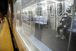 Subway riders wear protective masks and gloves on a sparsely populated car during morning hours due to COVID-19 concerns that are driving down ridership, Thursday, March 19, 2020, in New York. New York Gov. Andrew Cuomo tightened work-from-home rules Thursday as confirmed cases continued to climb in New York, an expected jump as testing becomes more widespread. But he stressed that roadblocks and martial law for New York City were merely rumors. 