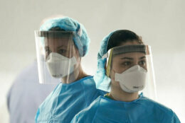 Two medical workers wearing masks and face shields.