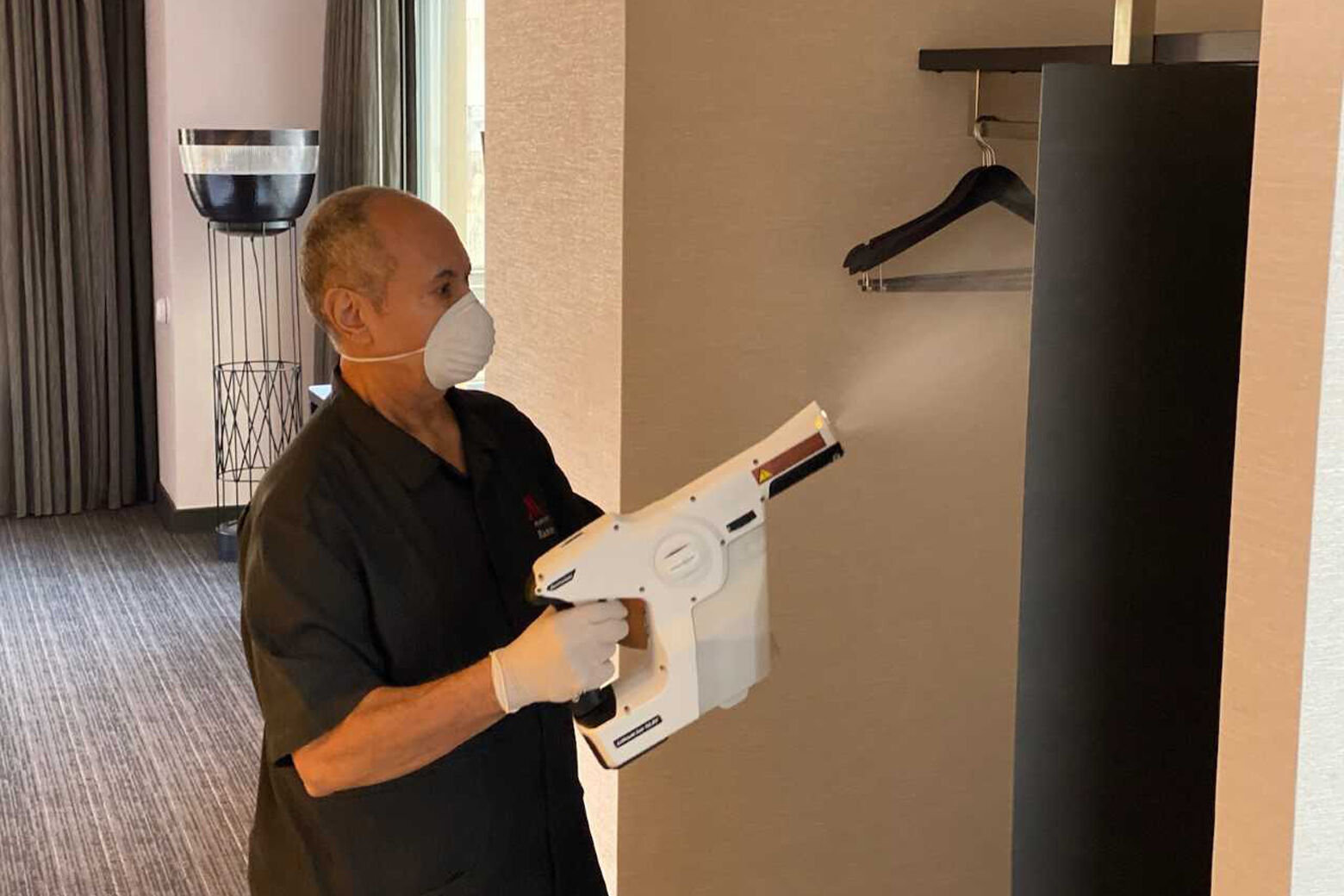 A Marriott employee uses an electrostatic sprayer.