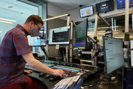 Man wearing a face mask, operates equipment in radio studio.