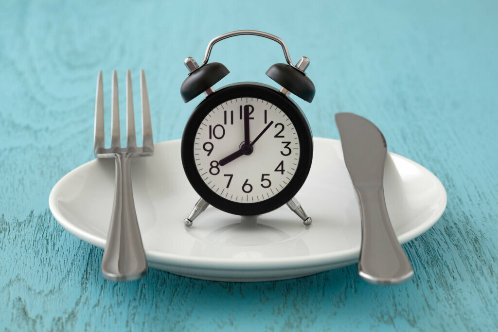 Clock on a plate with fork and knife.