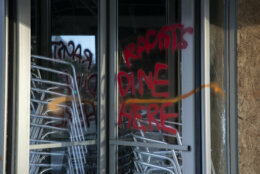 Spray paint the reads "Racists Dine Here" is seen on a revolving door or a restaurant near the White House in Washington, Monday, June 1, 2020, after a boring of protests over the death of George Floyd. Floyd died after being restrained by Minneapolis police officers. (AP Photo/Carolyn Kaster)