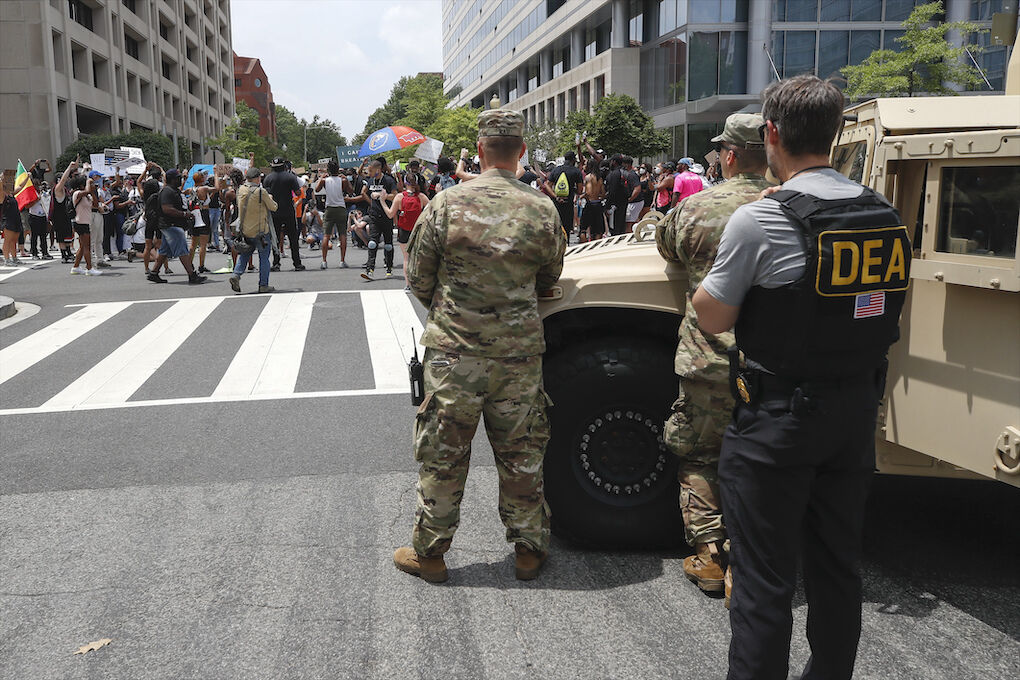 As a Drug Enforcement Agency police office and National Guard soldiers watch, demonstrators protest Saturday, June 6, 2020, in Washington, over the death of George Floyd, a black man who was in police custody in Minneapolis. Floyd died after being restrained by Minneapolis police officers. (AP Photo/Alex Brandon)