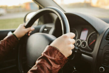 Close-up of hands on car steering wheel at 10 and 2