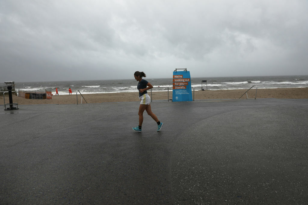 NEW YORK, NEW YORK - AUGUST 04: A woman runs along a deserted boardwalk in Rockaway, Queens as Tropical Storm Isaias churns its way up the East Coast on August 04, 2020 in New York City.The storm, which regained hurricane strength Monday night, is expected to bring heavy rainfall, lightning, strong winds and flooding to the New York City area on Tuesday afternoon. (Photo by Spencer Platt/Getty Images)