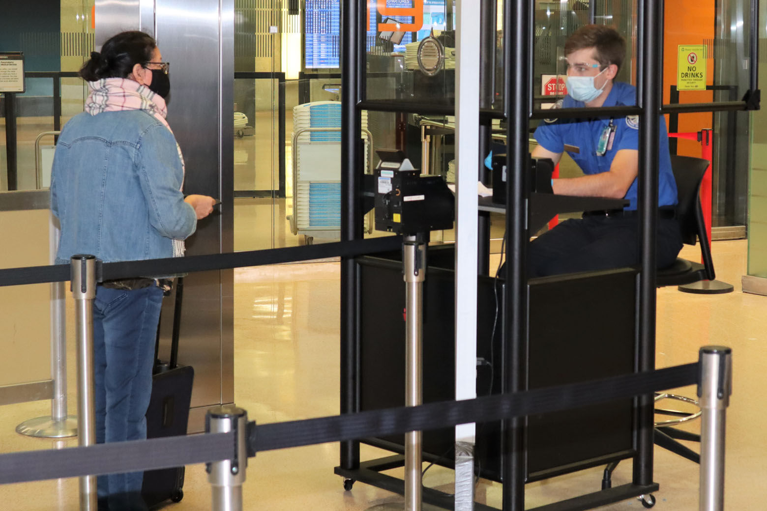 A TSA officer at Dulles International Airport sits behind a new acrylic shield designed to help prevent the spread of the coronavirus. (Courtesy TSA)