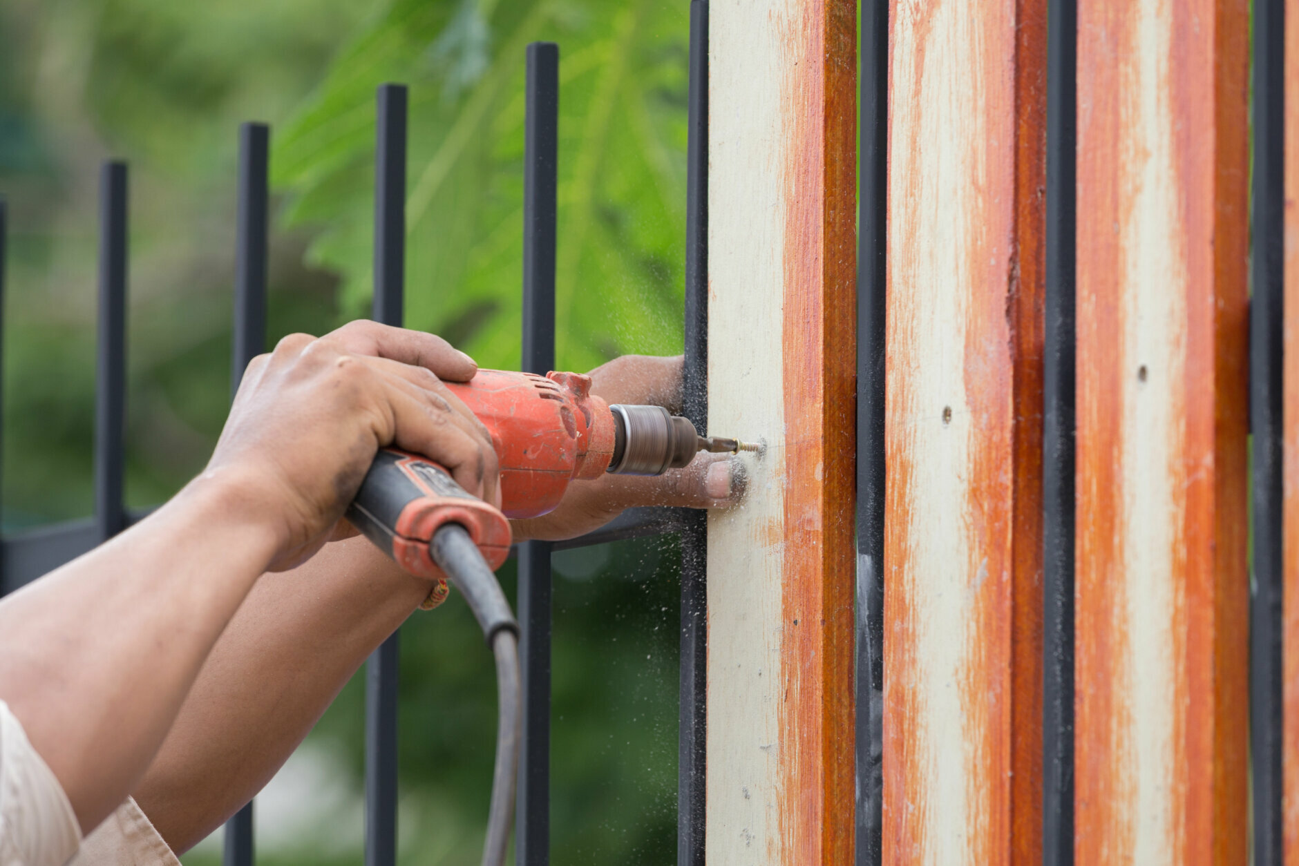 carpenter hands using electric drill on fence wood