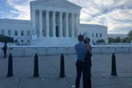 Two people embrace in front of Supreme Court