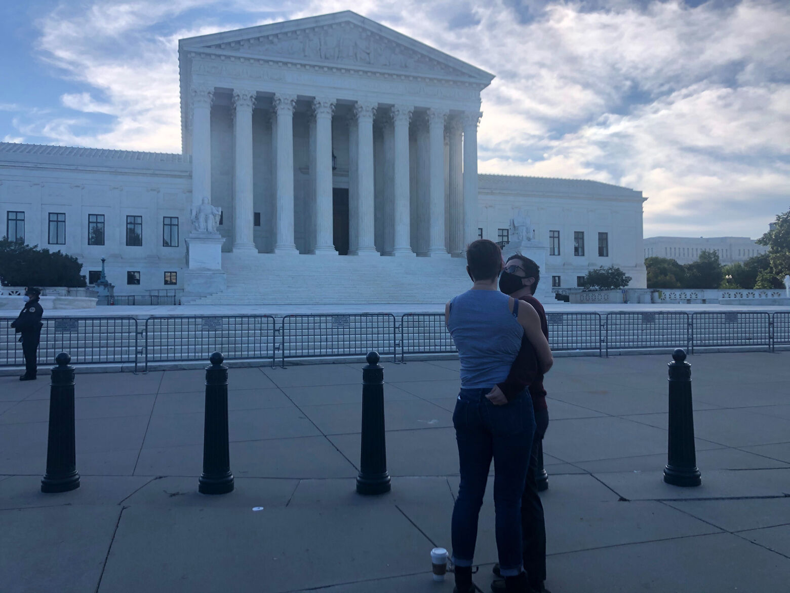 Two people embrace in front of Supreme Court