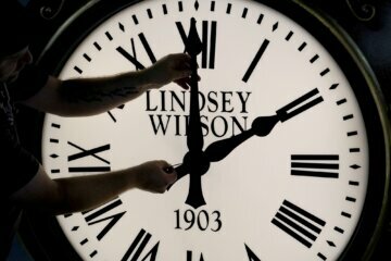 Dan LaMoore adjusts the hands on a Seth Thomas Post Clock at Electric Time Company, Friday, Oct. 23, 2020, in Medfield, Mass. Daylight saving time ends at 2 a.m. local time Sunday, Nov. 1, 2020, when clocks are set back one hour. (AP Photo/Elise Amendola)
