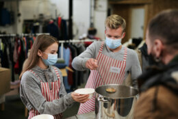Volunteers serving hot soup for ill and homeless in community charity donation center, food bank and coronavirus concept.