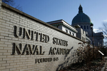 FILE - This Jan. 9, 2014 file photo shows a sign outside of an entrance to the U.S. Naval Academy campus in Annapolis, Md. A U.S. Naval Academy midshipman has asked a federal judge in Maryland to block his expulsion over messages he posted on social media, including one in which he said Breonna Taylor received â€œjusticeâ€ when police killed the Black woman during a drug raid on her Kentucky home. U.S. District Judge Ellen Hollander didn't immediately rule Friday, Oct. 30, 2020 after presiding over a hearing on Chase Standageâ€™s request for an order allowing him to graduate. (AP Photo/Patrick Semansky, File)