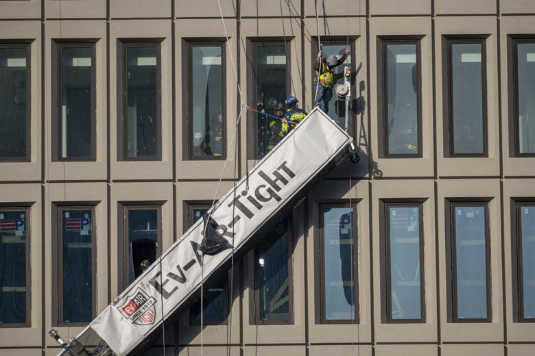 A worker stands on the end of a dangling scaffold as he waits to be rescued following an explosion at Baltimore Gas and Electric's offices, Wednesday, Dec. 23, 2020.  Twenty-one of the victims were brought to area hospitals following the explosion with a partial roof collapse. The cityâ€&#x2122;s fire department tweeted that at least nine of the victims were in critical condition, while another was in serious condition. (Jerry Jackson/The Baltimore Sun via AP)