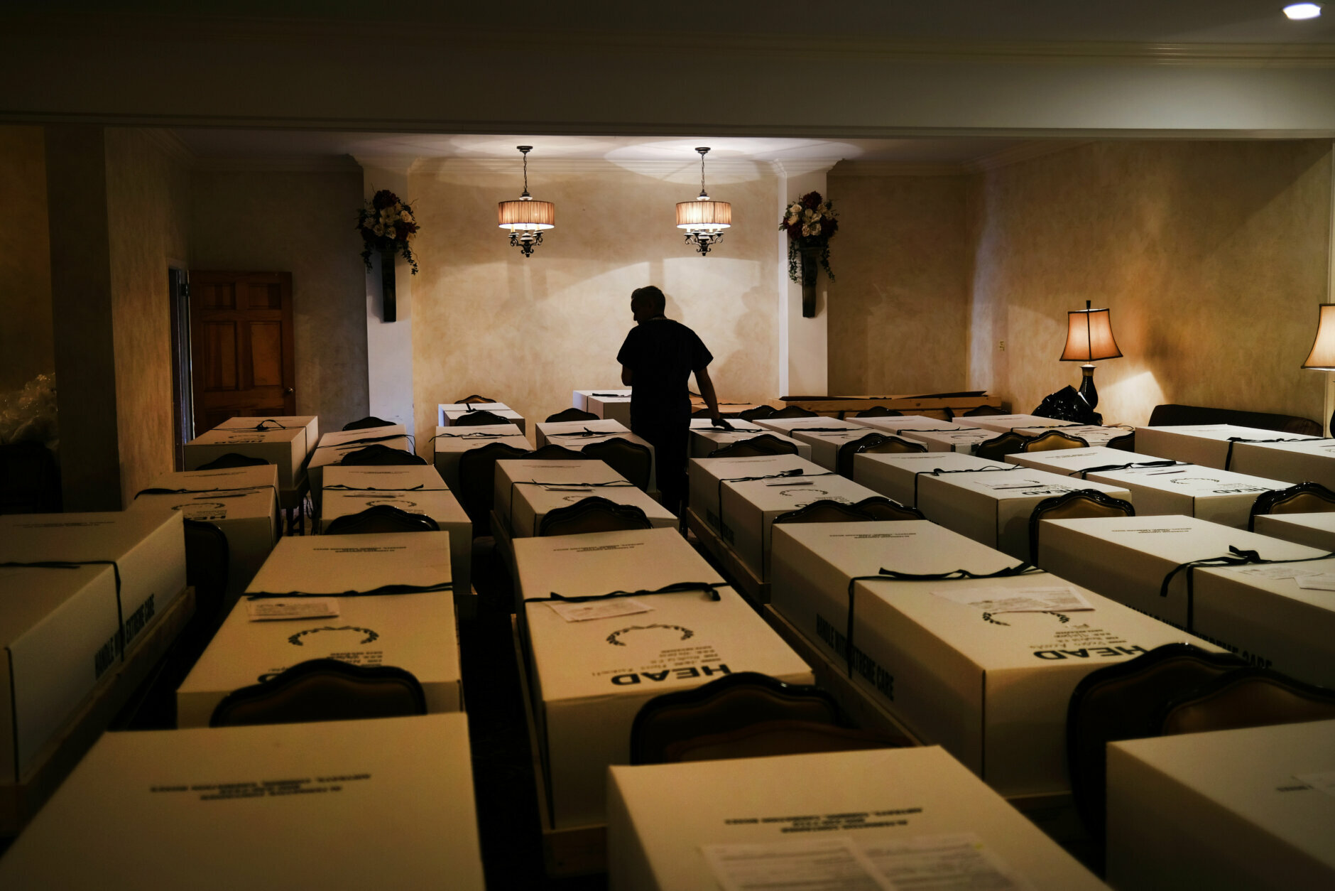 Man stands amid containers holding bodies at a funeral home.