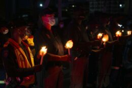 Frontline workers attend a candlelight ceremony on New Year's Eve on the famed Nelson Mandela Bridge in downtown Johannesburg Thursday, Dec. 31, 2020. Many South Africans will swap firecrackers for candles to mark New Year's Eve amid COVID-19 restrictions including a nighttime curfew responding to President Cyril Ramaphosa's call to light a candle to honor those who have died in the COVID-19 pandemic and the health workers who are on the frontline of battling the disease.. (AP Photo/Denis Farrell)