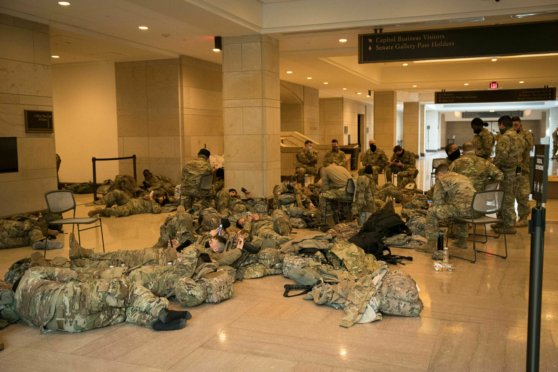 National Guard rest within the halls of the U.S. Capitol visitor center between shifts on Jan. 13, 2021. More than 20,000 armed guardsmen are expected to provide security in the nation's capital amid threats against the inauguration of President-elect Joe Biden. (WTOP/Alejandro Alvarez)
