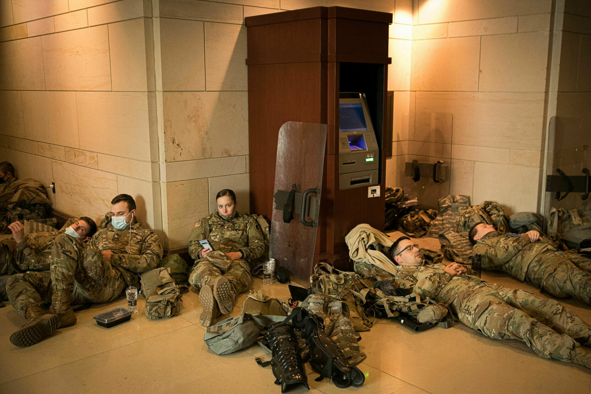 Members of the National Guard rest beside an ATM in the Capitol visitor center on Jan. 13, 2021. More than 20,000 armed guardsmen are expected to provide security in the nation's capital amid threats against the inauguration of President-elect Joe Biden. (WTOP/Alejandro Alvarez)