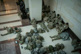 Soldiers rest near a statue of Frederick Douglass in the U.S. Capitol visitor center shortly after their arrival in the District on Jan. 13, 2021. More than 20,000 armed guardsmen are expected to provide security in the nation's capital amid threats against the inauguration of President-elect Joe Biden. (WTOP/Alejandro Alvarez)