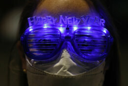 Alejandra Paiz, a tourist from Guatemala who is visiting Mexico for the holidays with a friend and their respective sons, wears festive glasses as the group marks New Year's Eve at the Angel of Independence monument in Mexico City, just after midnight on Friday, Jan. 1, 2021. Although Mexico City cancelled its annual New Year's celebration to curb the spread of the COVID-19 pandemic, dozens of people came out in small groups to mark midnight with selfies and video calls from the iconic city landmark.(AP Photo/Rebecca Blackwell)