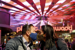 A couple wearing face masks kisses as they celebrate New Year's Eve along the Las Vegas Strip Thursday, Dec 31, 2020, in Las Vegas. (AP Photo/David Becker)