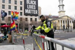 A Metropolitan Police officer secures fencing keeping pedestrian's out of a section of Black Lives Matter Plaza, next to a few counter-protesters, Tuesday, Jan. 5, 2021, in Washington, ahead of an expected rally in support of President Donald Trump. (AP Photo/Jacquelyn Martin)