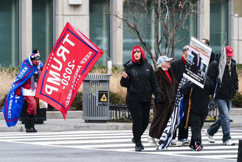 Supporters of President Donald Trump walk with signs and flags past Black Lives Matter Plaza, Tuesday, Jan. 5, 2021, in Washington, ahead of expected rallies in support of Trump. (AP Photo/Jacquelyn Martin)