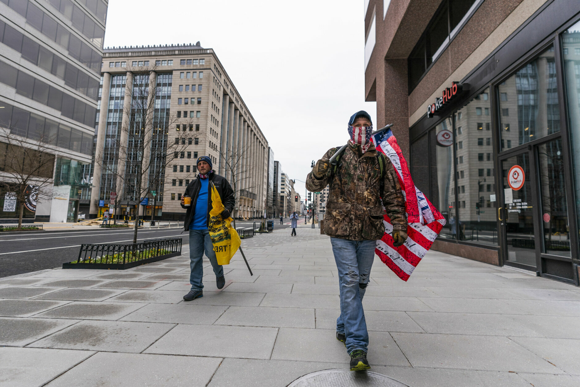 Supporter of President Donald Trump Justine Lagesse, right, from southern Illinois, carries a flag as he walks at an almost deserted street in downtown Washington, Tuesday, Jan. 5, 2021 in Washington. (AP Photo/Manuel Balce Ceneta)