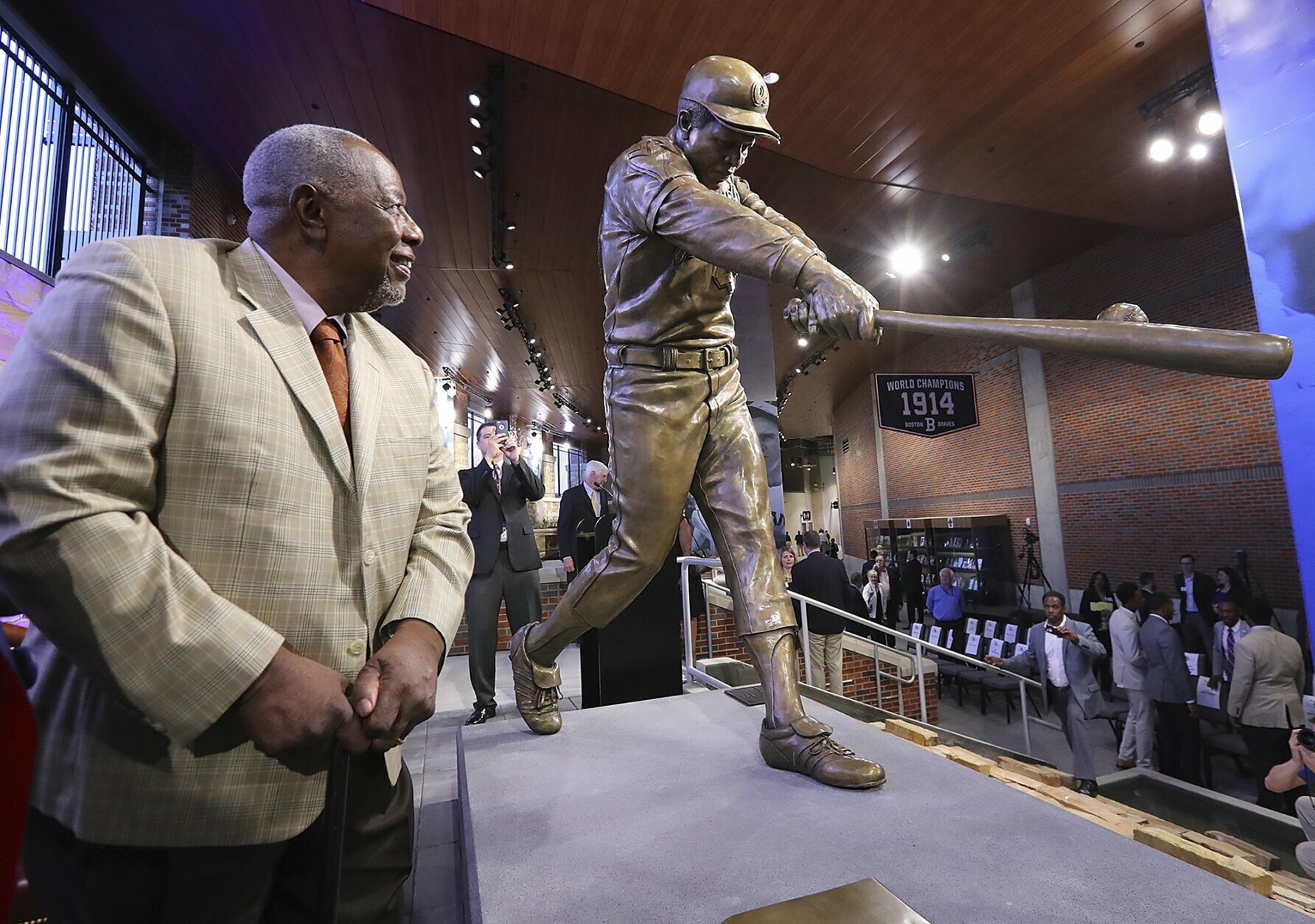 FILE-  In this March 29, 2017, file photo, Hank Aaron looks at his new statue in Monument Garden at SunTrust Park, home of the Atlanta Braves, after the unveiling ceremony in Atlanta. Hank Aaron, who endured racist threats with stoic dignity during his pursuit of Babe Ruth but went on to break the career home run record in the pre-steroids era, died early Friday, Jan. 22, 2021. He was 86. The Atlanta Braves said Aaron died peacefully in his sleep. No cause of death was given. (Curtis Compton/Atlanta Journal-Constitution via AP, File)