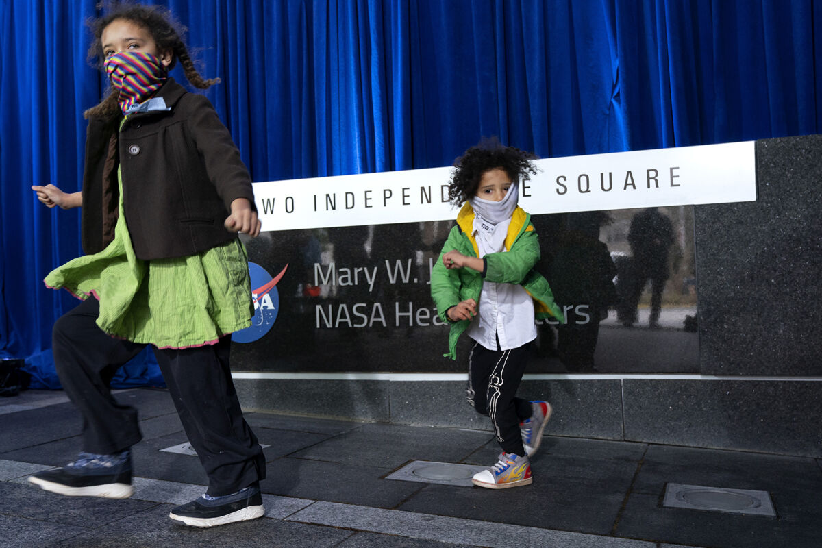 Faris Nunn, 7, left, and her brother King Nunn, 4, "fly" past after taking a photograph after a ceremony officially naming the NASA Headquarters building in honor of Mary W. Jackson, who was the first Black female engineer at NASA, Friday, Feb. 26, 2021, in Washington. "My daughter is really into NASA," says her mother Lora Nunn, "and it's Black History Month, so we wanted to come and see the renaming today." (AP Photo/Jacquelyn Martin)