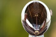 A man is reflected in the Lombardi Trophy at the NFL Experience Thursday, Feb. 4, 2021, in Tampa, Fla. The city is hosting Sunday's Super Bowl football game between the Tampa Bay Buccaneers and the Kansas City Chiefs. (AP Photo/Charlie Riedel)