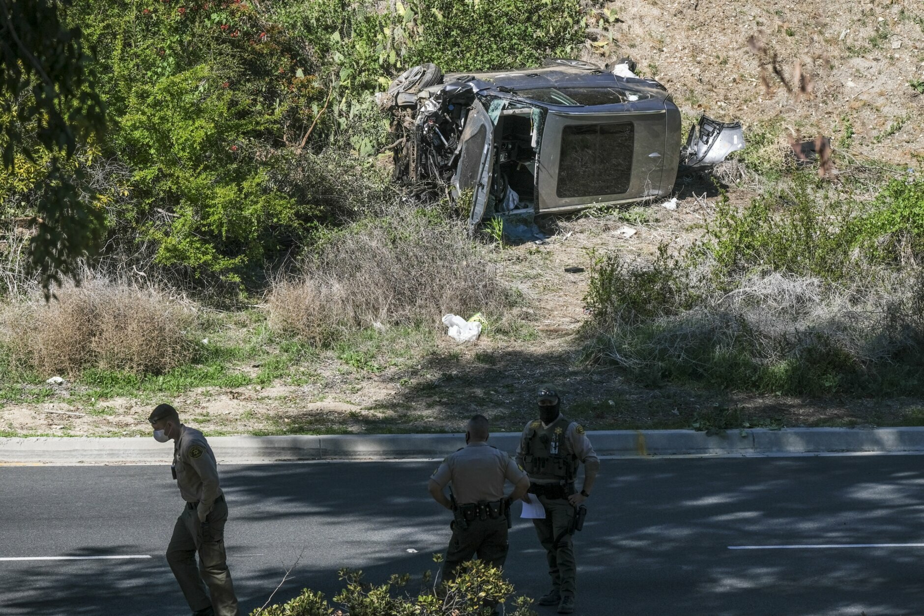 A vehicle rests on its side after a rollover accident involving golfer Tiger Woods along a road in the Rancho Palos Verdes suburb of Los Angeles on Tuesday, Feb. 23, 2021. Woods suffered leg injuries in the one-car accident and was undergoing surgery, authorities and his manager said. (AP Photo/Ringo H.W. Chiu)