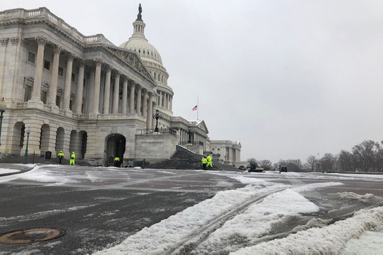 Workers are seen clearing ice and snow from the steps of the U.S. Capitol.