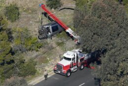 Workers move a vehicle after a rollover accident involving golfer Tiger Woods Tuesday, Feb. 23, 2021, in the Rancho Palos Verdes section of Los Angeles. Woods suffered leg injuries in the one-car accident and was undergoing surgery, authorities and his manager said. (AP Photo/Mark J. Terrill)