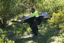 A worker moves debris after a rollover accident involving golfer Tiger Woods Tuesday, Feb. 23, 2021, in the Rancho Palos Verdes section of Los Angeles. Woods suffered leg injuries in the one-car accident and was undergoing surgery, authorities and his manager said. (AP Photo/Marcio Jose Sanchez)