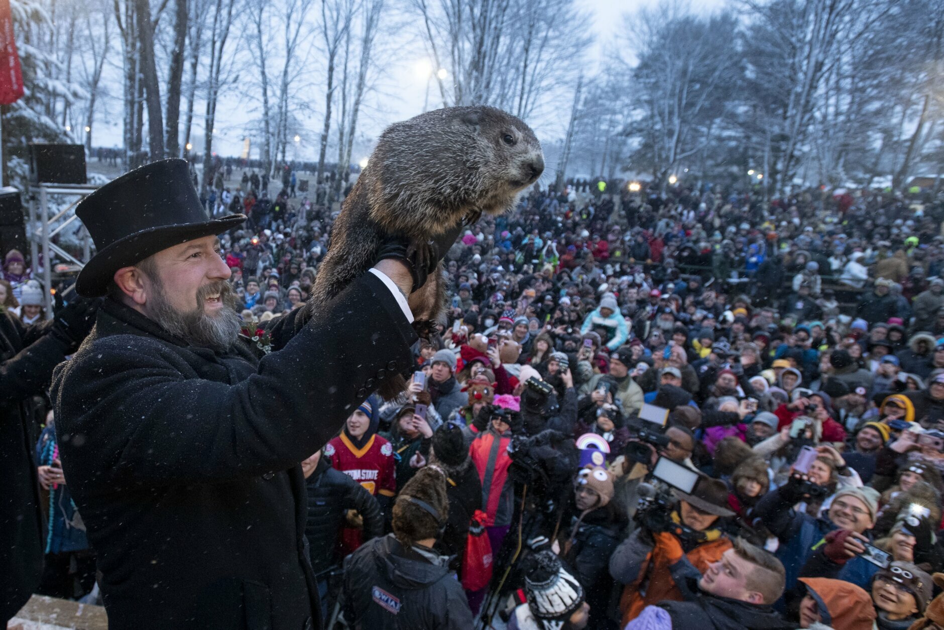 FILE - In this Feb. 2, 2020 file photo, Groundhog Club co-handler Al Dereume holds Punxsutawney Phil during the 134th celebration of Groundhog Day on Gobbler's Knob in Punxsutawney, Pa. The coronavirus pandemic means Groundhog Day won't be the same in the Pennsylvania town long associated with a prognosticating rodent. Organizers said Punxsutawney Phil will predict whether spring will come early or winter will last longer in 2021 without the usual crowds who gather at Gobbler's Knob.  Phil and his inner circle on Feb. 2 will deliver the prediction virtually by means of a live internet steam and website, organizers said.  