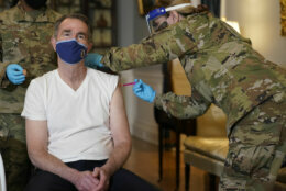 Virginia Gov. Ralph Northam receives a COVID-19 vaccination from Lt. Col. Kris Clark, of the Virginia Air National Guard at the Governors Mansion in Richmond, Va., Monday, March 15, 2021.  Northam got a shot of the Johnson &amp; Johnson coronavirus vaccine, joining the growing number of Virginians who are being inoculated against the potentially deadly disease.  (AP Photo/Steve Helber)