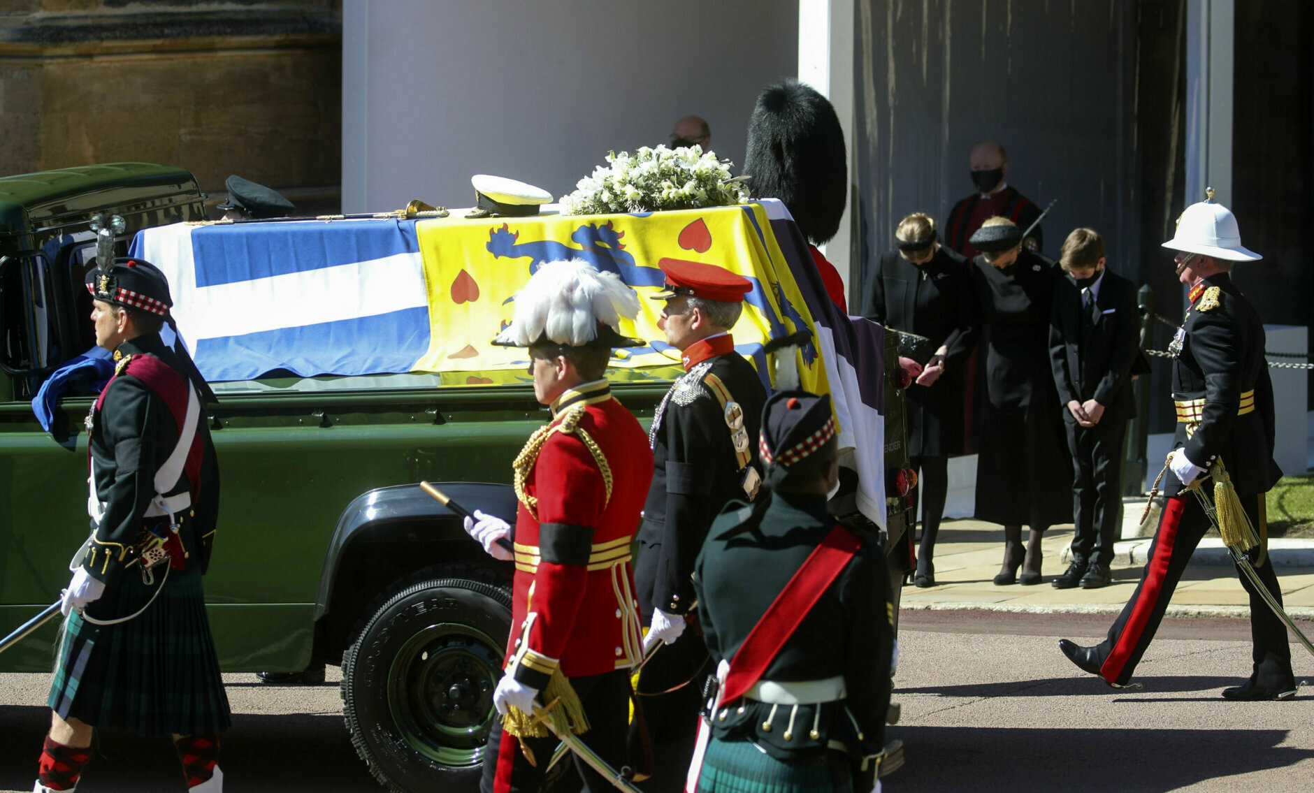 The Duke of Edinburgh's coffin, covered with his Personal Standard, is carried on the purpose built Land Rover Defender, drives past from left Lady Louise Windsor, the Countess of Wessex and James, Viscount Severn with heads bowed, at the Galilee Porch of St George's Chapel, at Windsor Castle, Windsor, England, Saturday April 17, 2021, during the funeral of Britain's Prince Philip. Prince Philip died April 9 at the age of 99 after 73 years of marriage to Britain's Queen Elizabeth II. (Steve Parsons/Pool via AP)