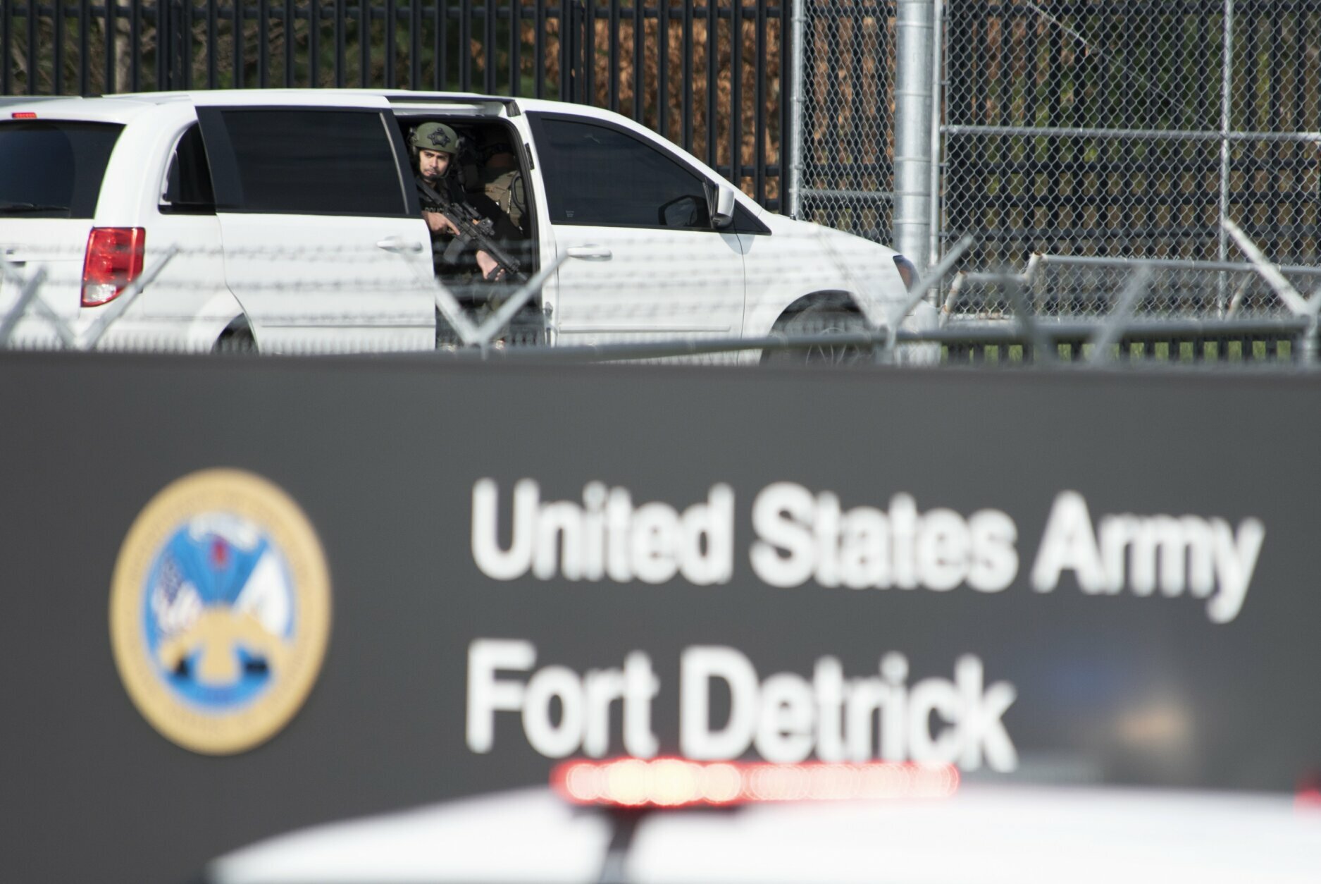 A member of the Frederick Police Department Special Response Team peers out of a minivan before the team entered Fort Detrick in a convoy of vans and sedans following a shooting in the Riverside Tech Park, near the Royal Farms on Monocacy Boulevard, Tuesday, April 6, 2021, in northeast Frederick, Md. Authorities say a Navy medic shot and critically wounded a few people at a Maryland business park before fleeing to the Fort Detrick Army base, where he was shot and killed. (Graham Cullen/The Frederick News-Post via AP)