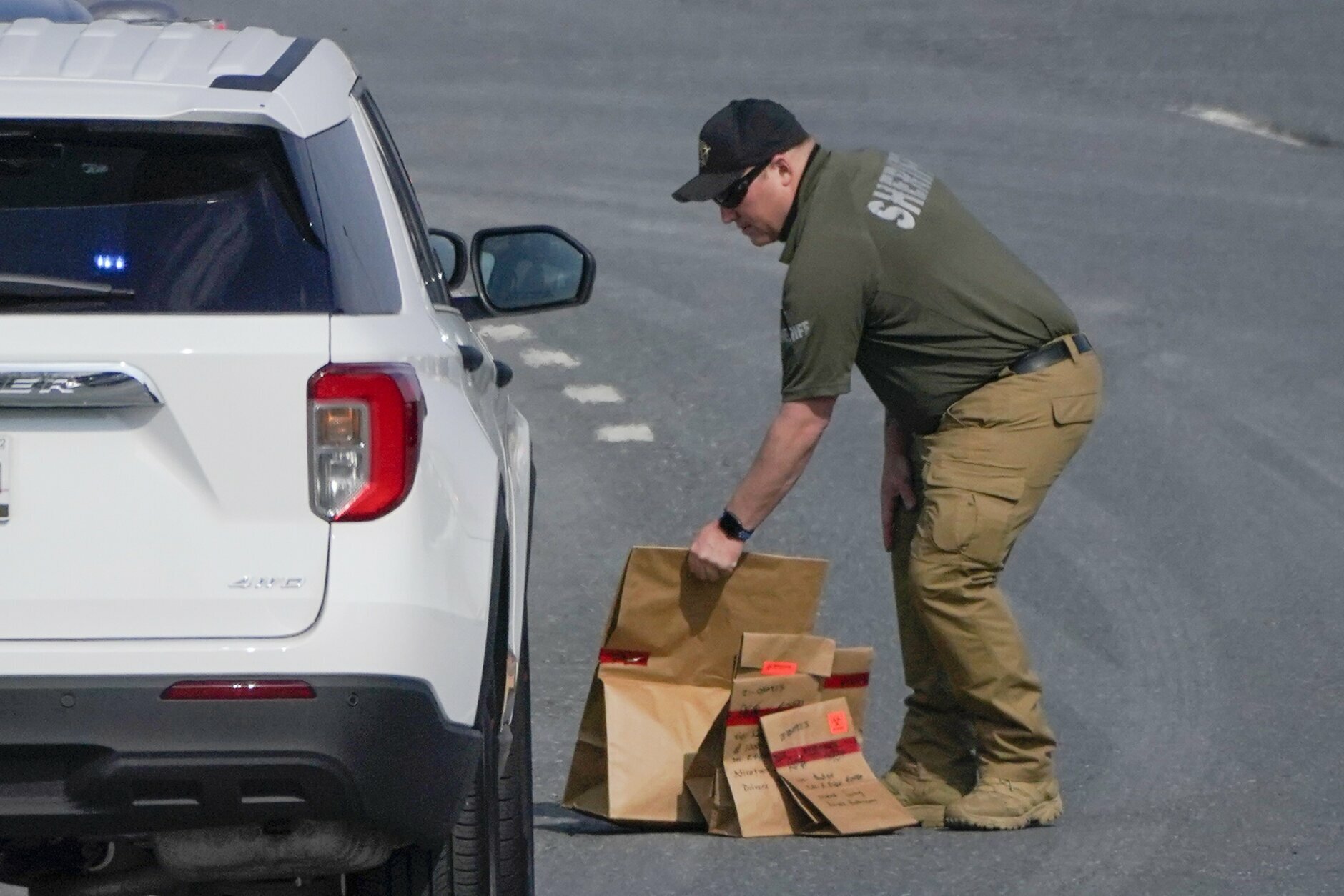 A sheriff's deputy from Frederick County, Md., puts paper bags with evidence into a police vehicle near the scene of a shooting at a business park in Frederick, Md., Tuesday, April 6, 2021. (AP Photo/Julio Cortez)