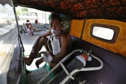 A COVID-19 patient breathes with the help of an oxygen mask as he waits inside an auto rickshaw to be attended to and admitted in a dedicated COVID-19 government hospital in Ahmedabad, India, Thursday, April 22, 2021. Indian authorities scrambled Saturday to get oxygen tanks to hospitals where COVID-19 patients were suffocating amid the world’s worst coronavirus surge, as the government came under increasing criticism for what doctors said was its negligence in the face of a foreseeable public health disaster. (AP Photo/Ajit Solanki)