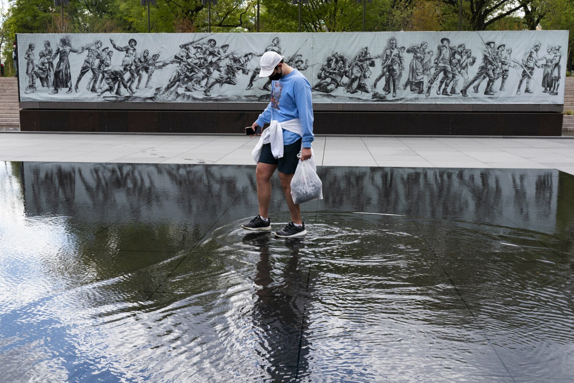 A man walks across a shallow water feature at the newly opened World War I Memorial, Friday, April 16, 2021, in Washington. (AP Photo/Jacquelyn Martin)